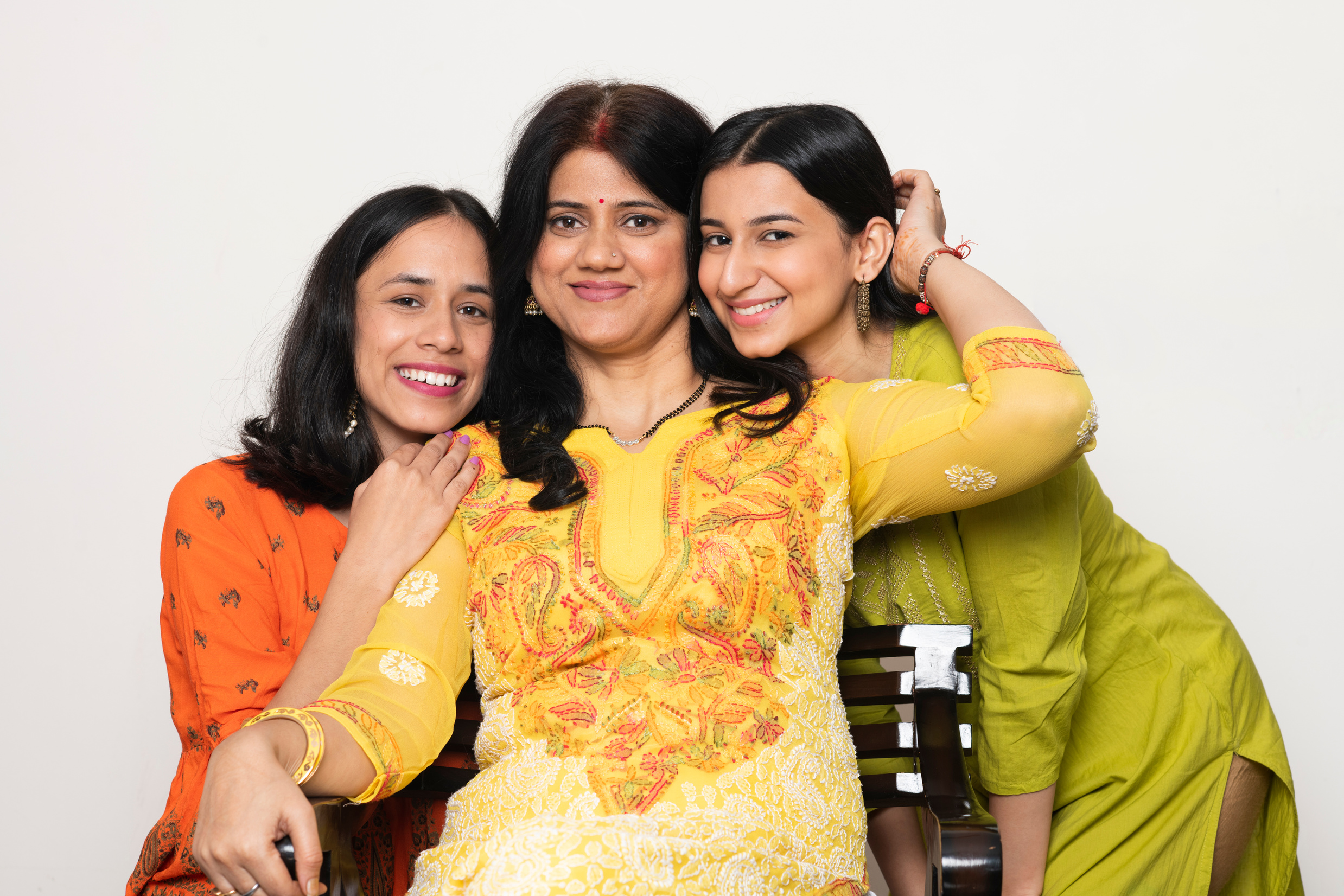 Two Smiling Daughters Embracing Their Mother